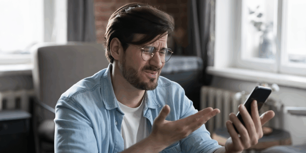 Frustrated customer looking at smartphone, representing someone urgently searching for repair services on Apple Maps.